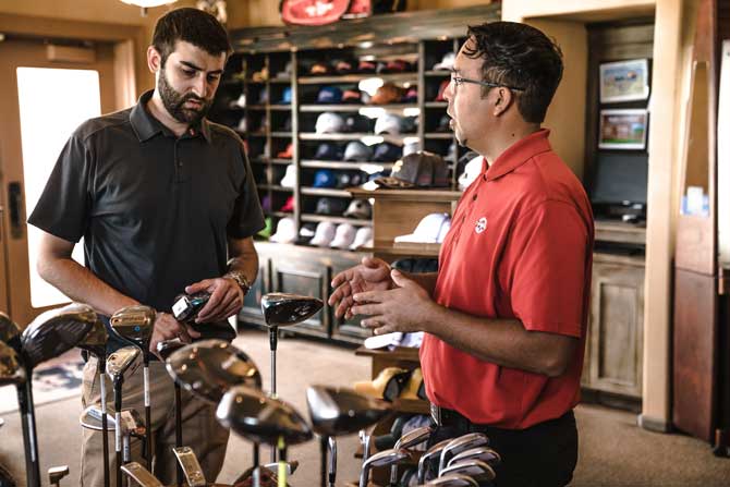 small business owner selling golf clubs to a young man